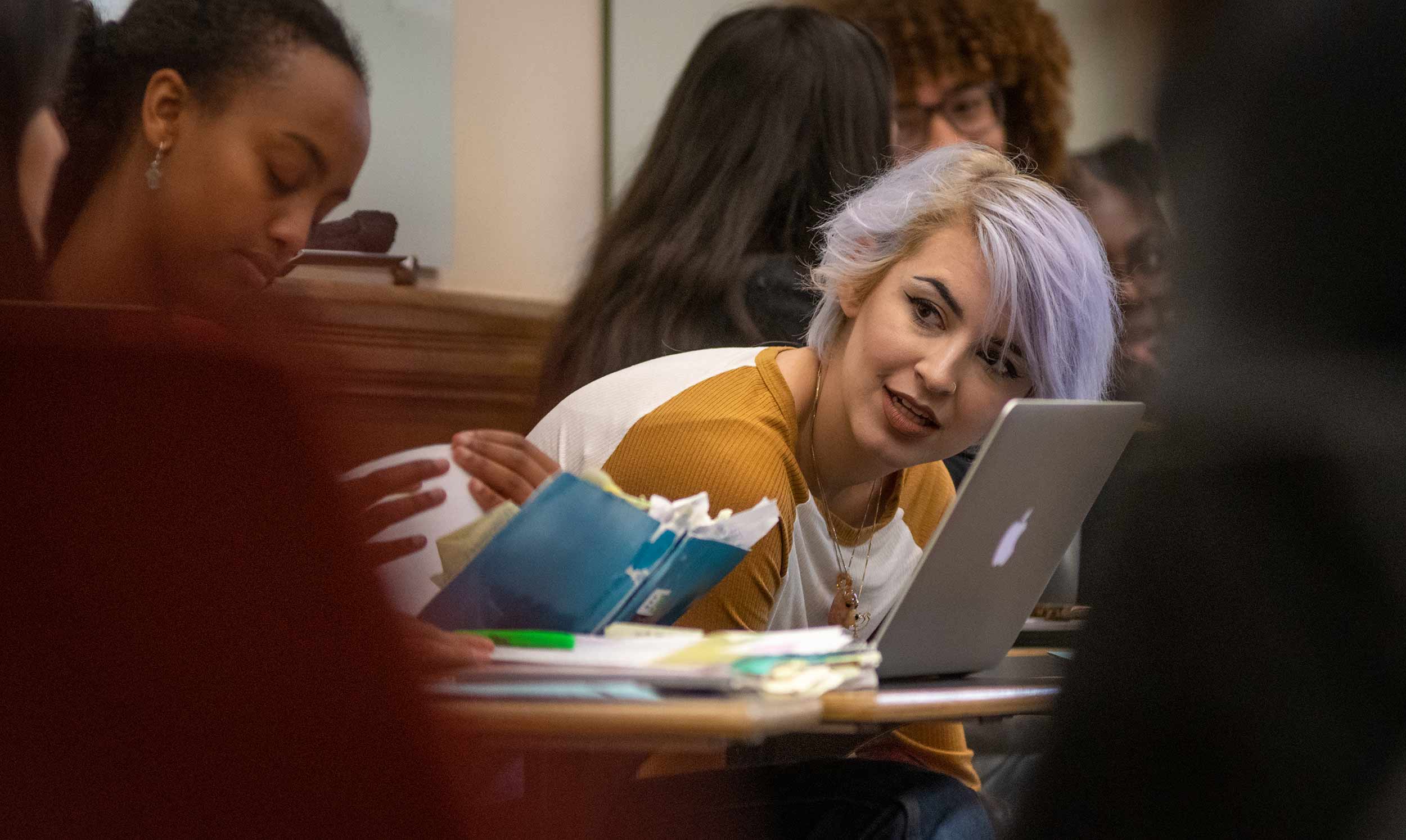 A student leans forward to speak to a peer during a class on class, status, and power