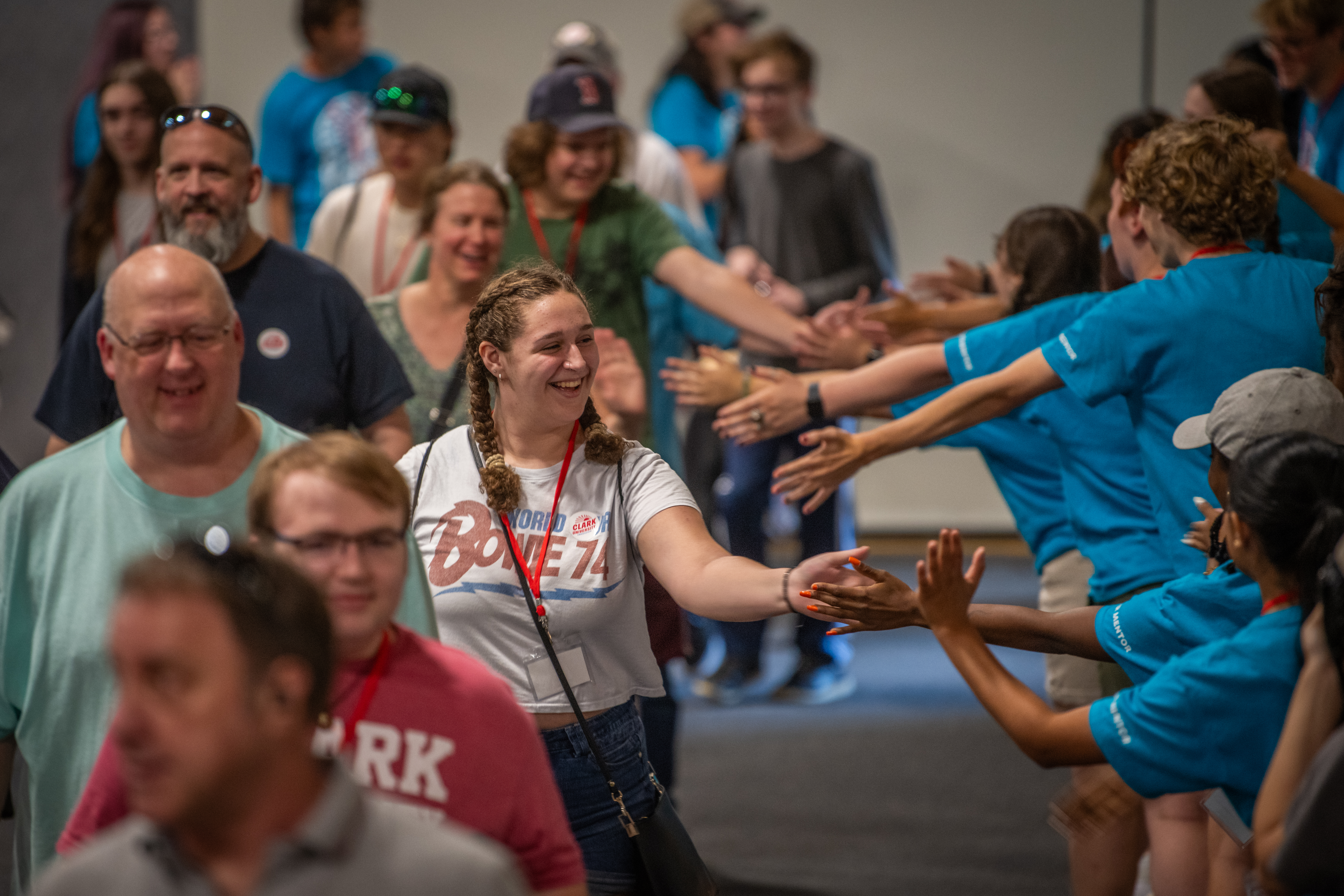 A photo of a student walking down a line high fiving a line of students in blue shirts