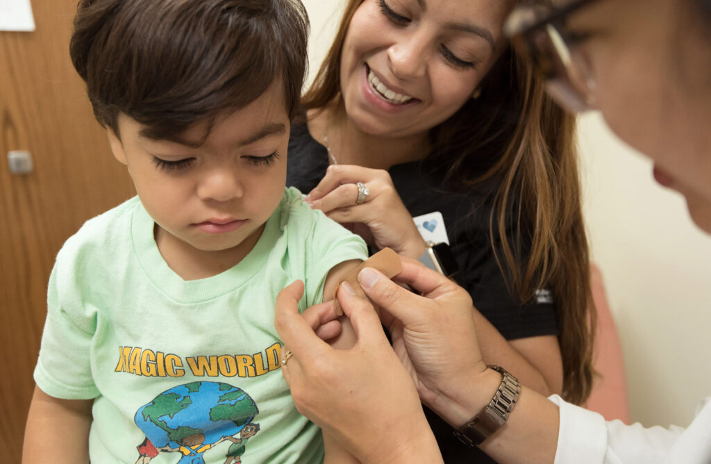 Close-up of a child sitting on his mother's lap, receiving health services