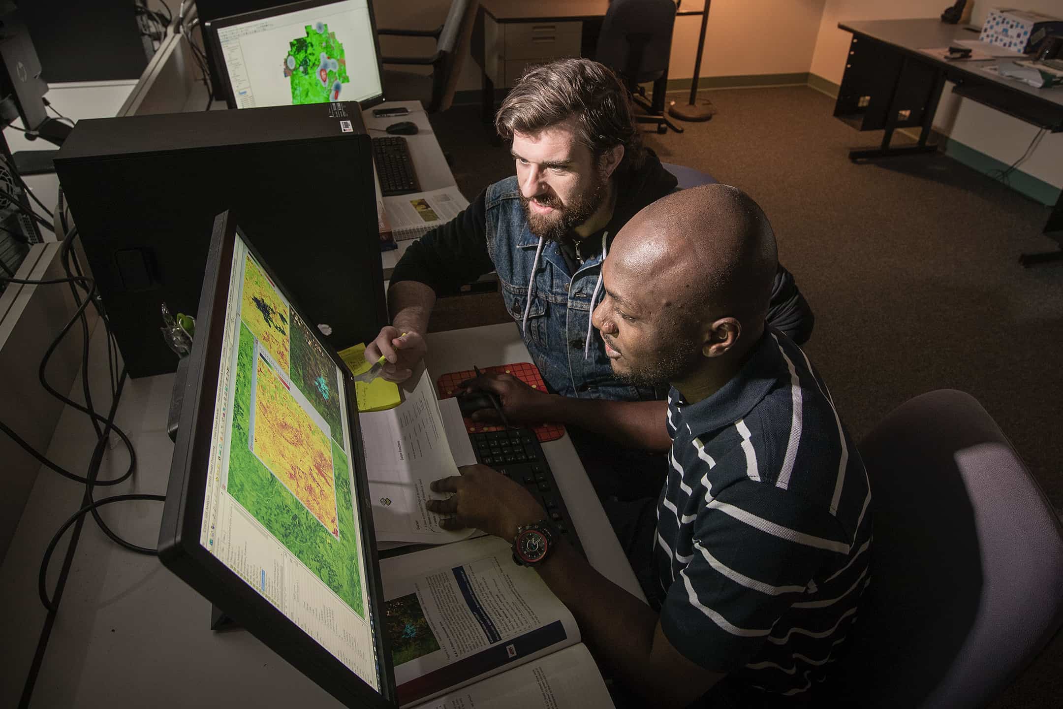 two students looking over geographic maps on computers