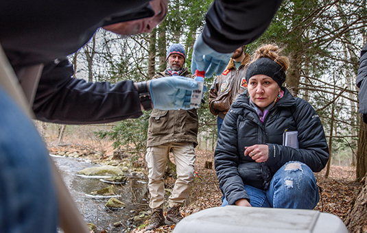 faculty member with students taking water samples