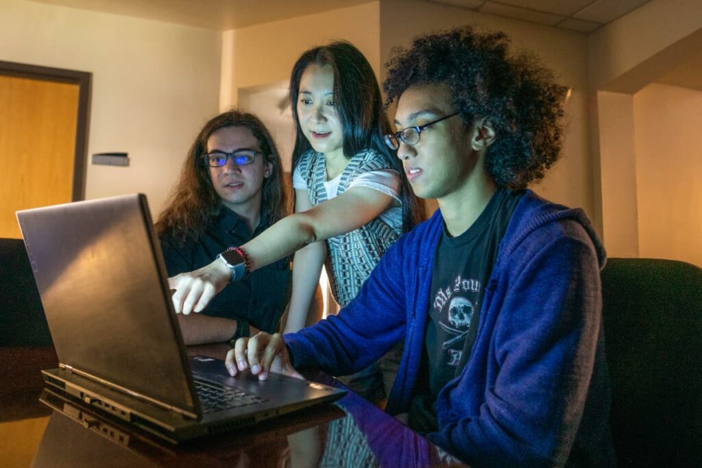 Students looking at laptop with professor