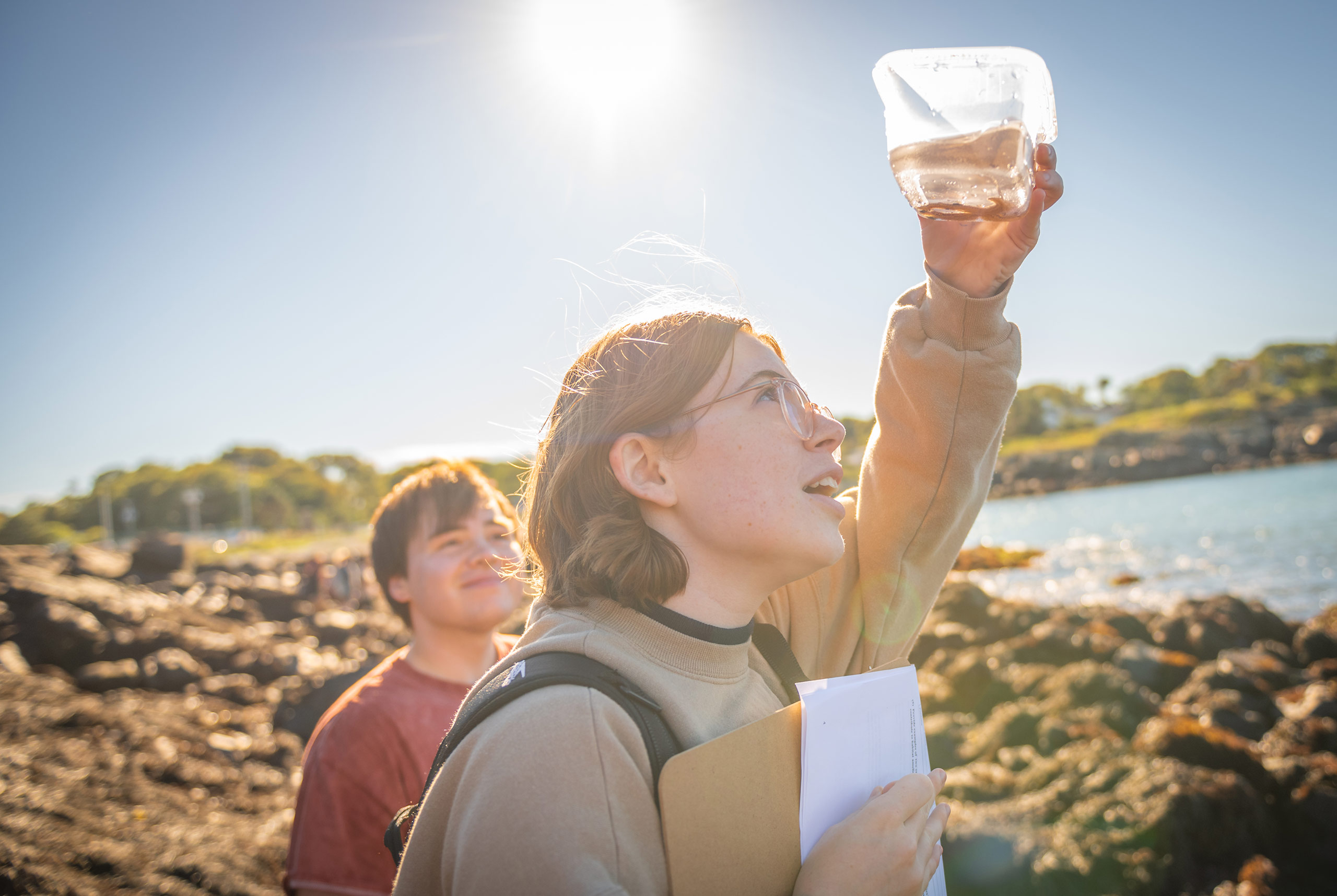 A biology student examines a specimen in the sunlight during a field trip to the beach in Nahant