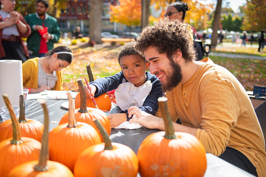 family weekend with student painting pumpkins with young child