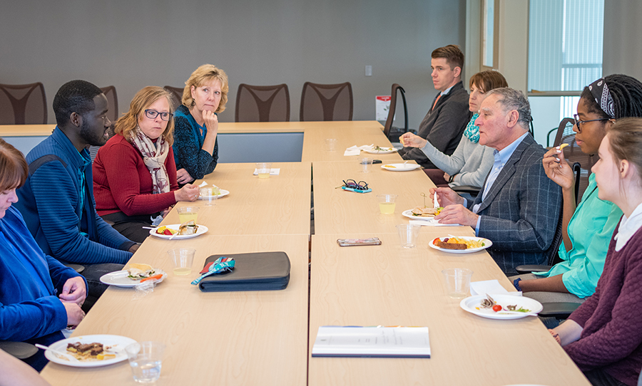 staff and students around table discussing subject