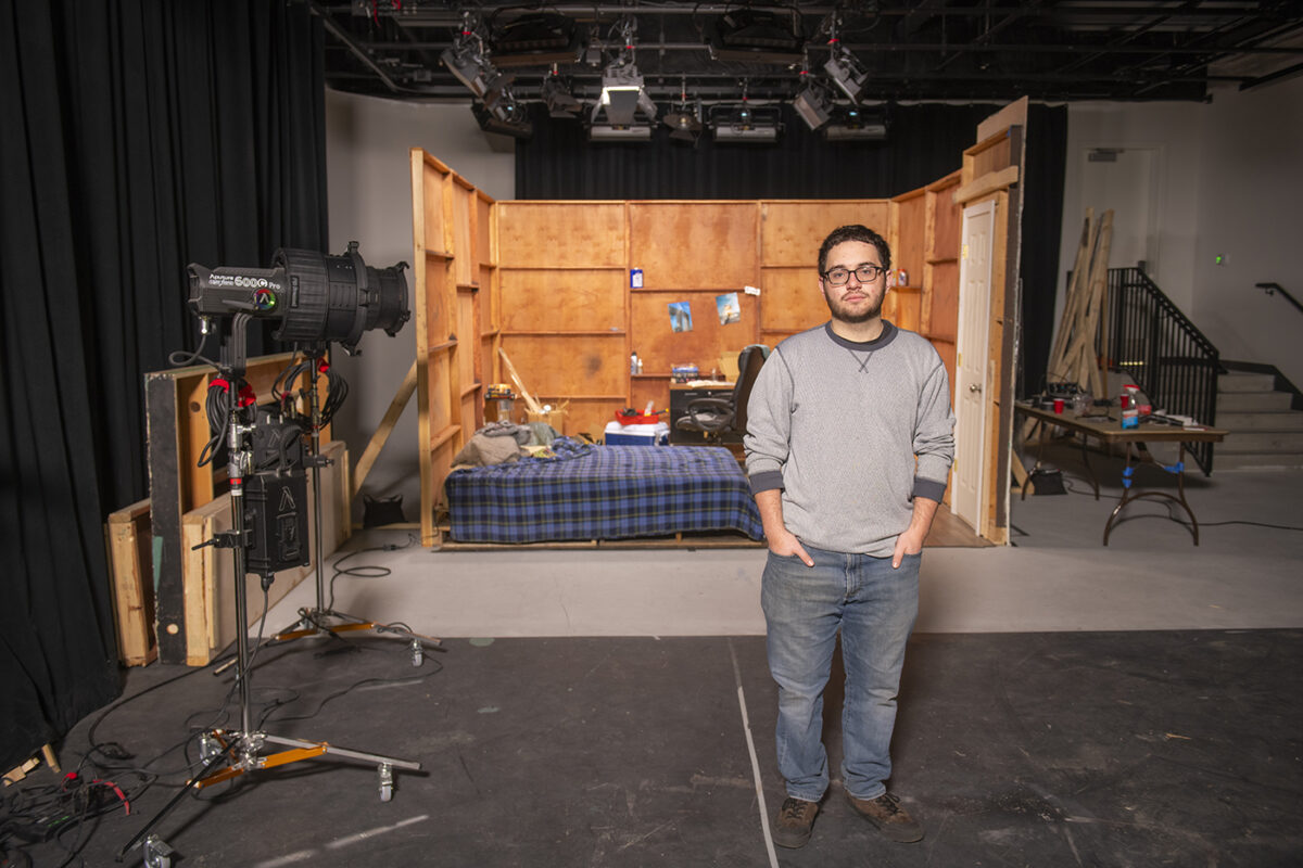 Student filmmaker Zeke Fairley ’25 stands on the set he created for the senior thesis film, , From the Cabin.