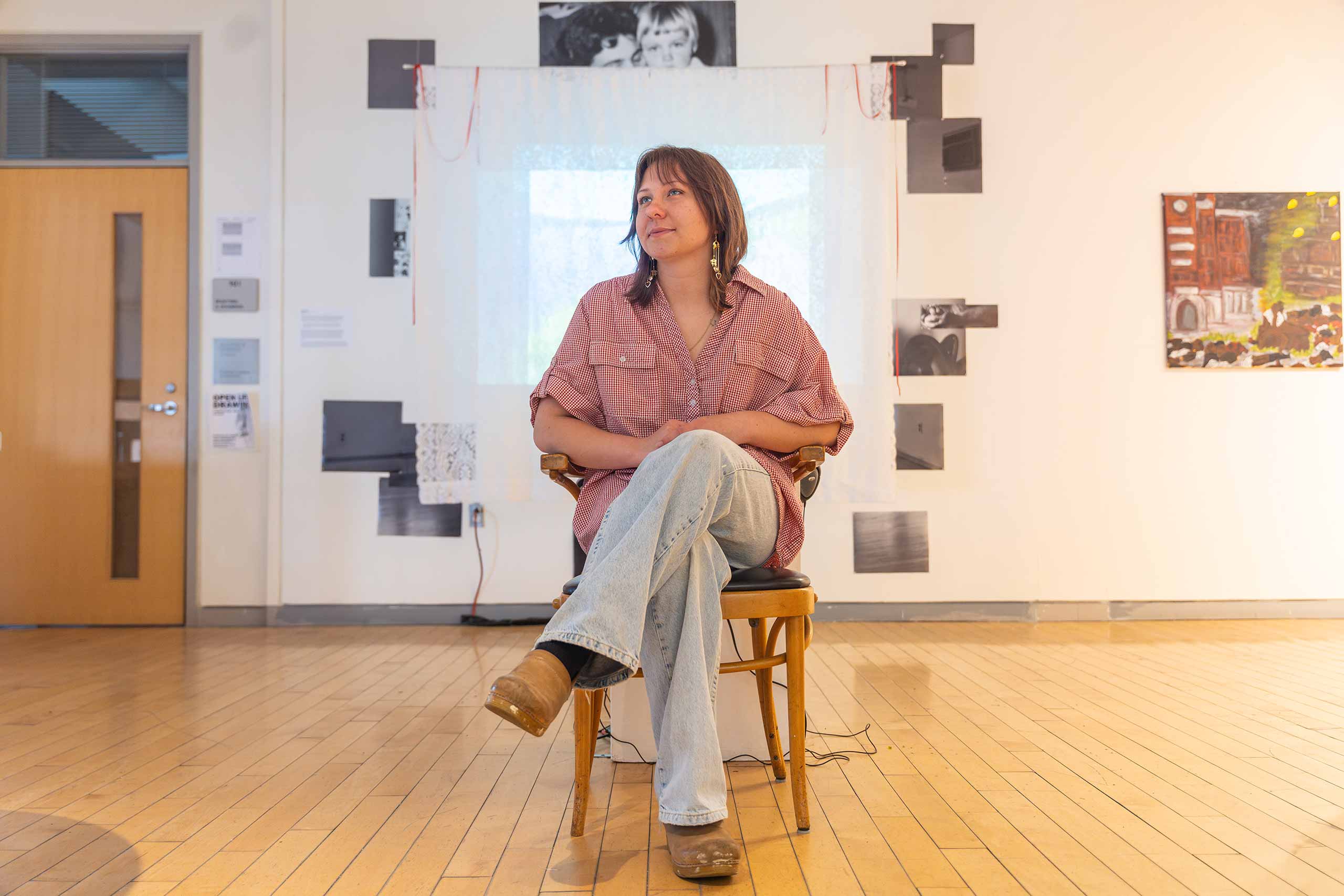 Renee Knowles sits in the gallery with their art thesis works on display.