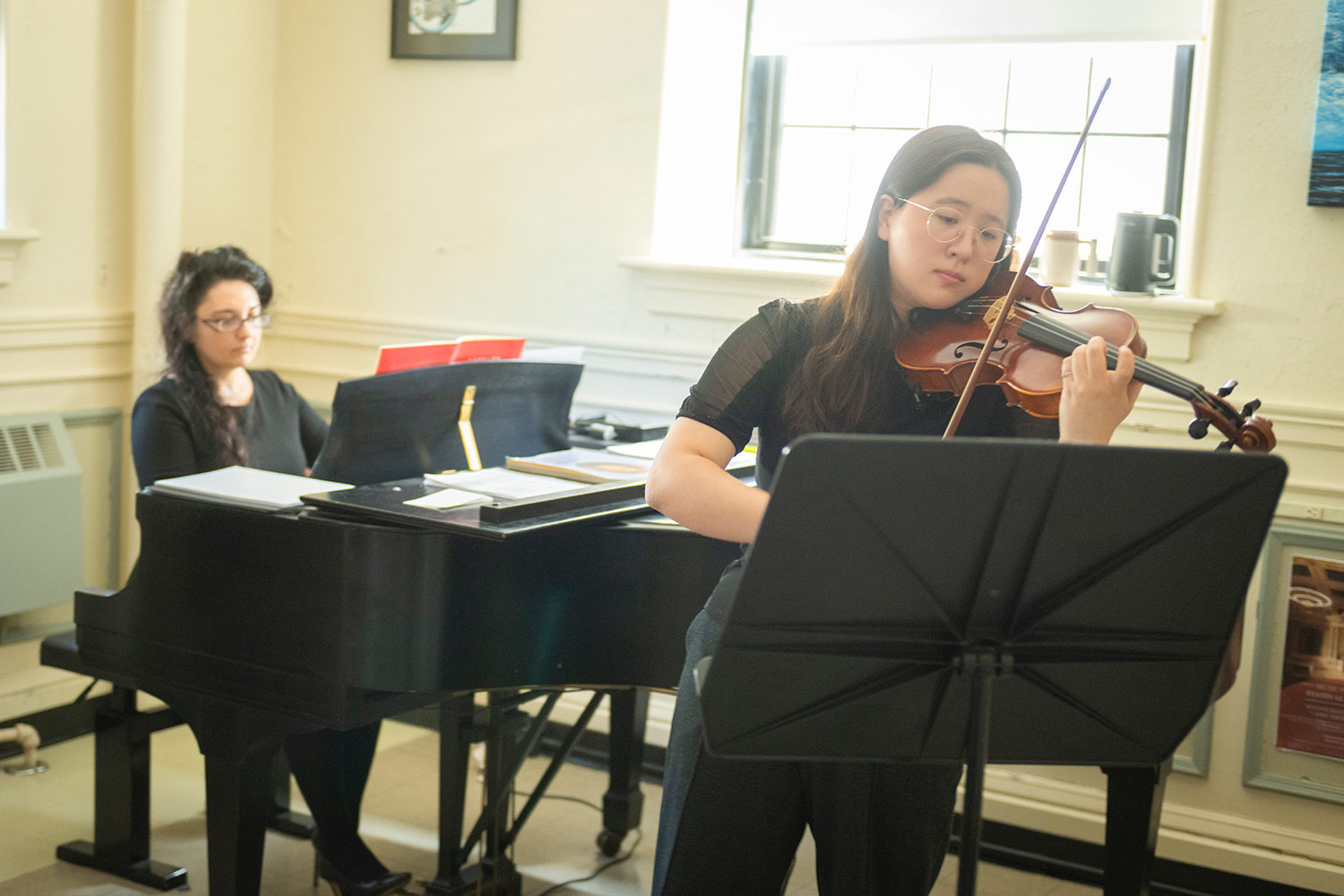 Music student, Erin Maynard practicing violin in a practice space, Estabrook Hall, Clark University
