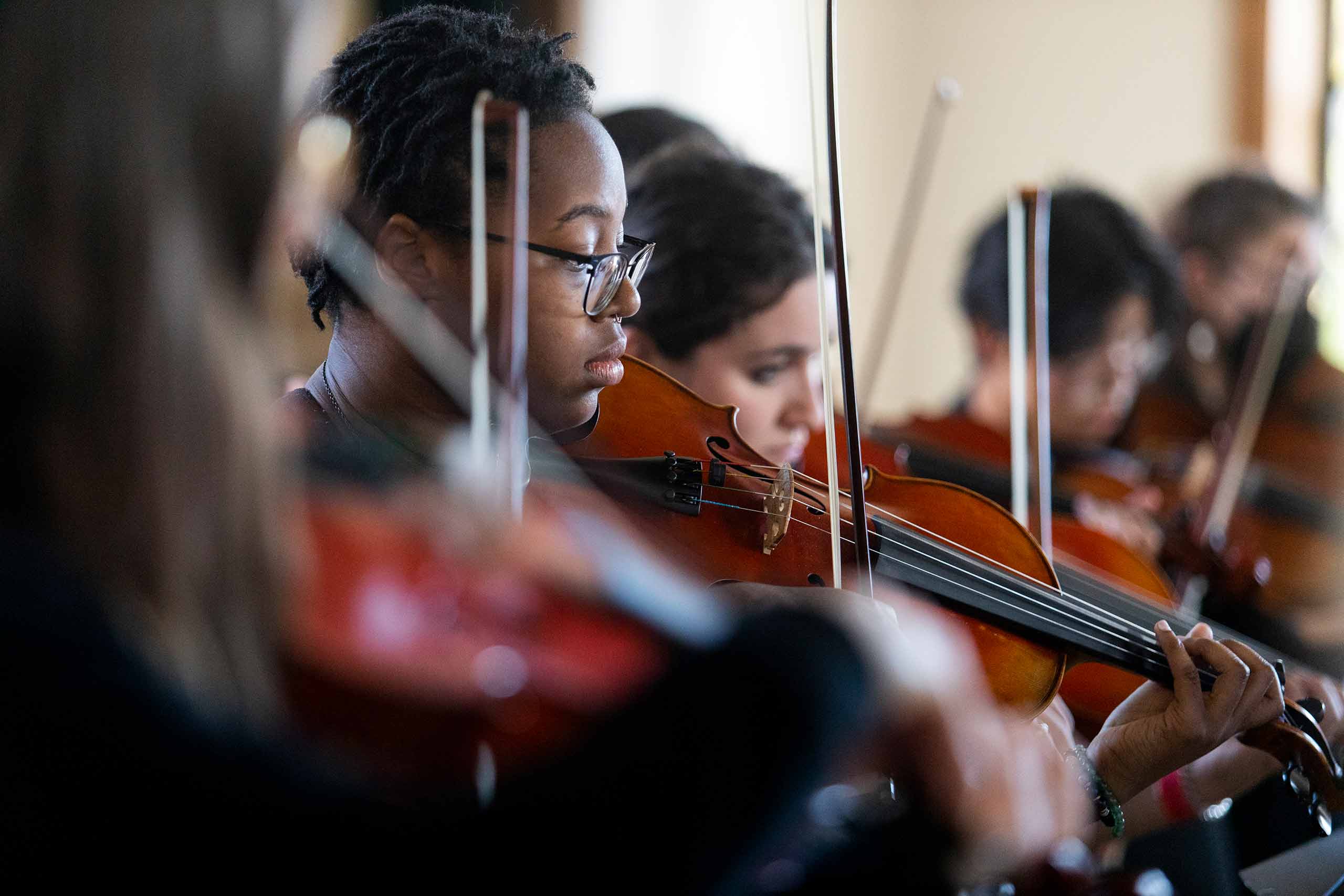 Students playing violins in an orchestra performance at family weekend
