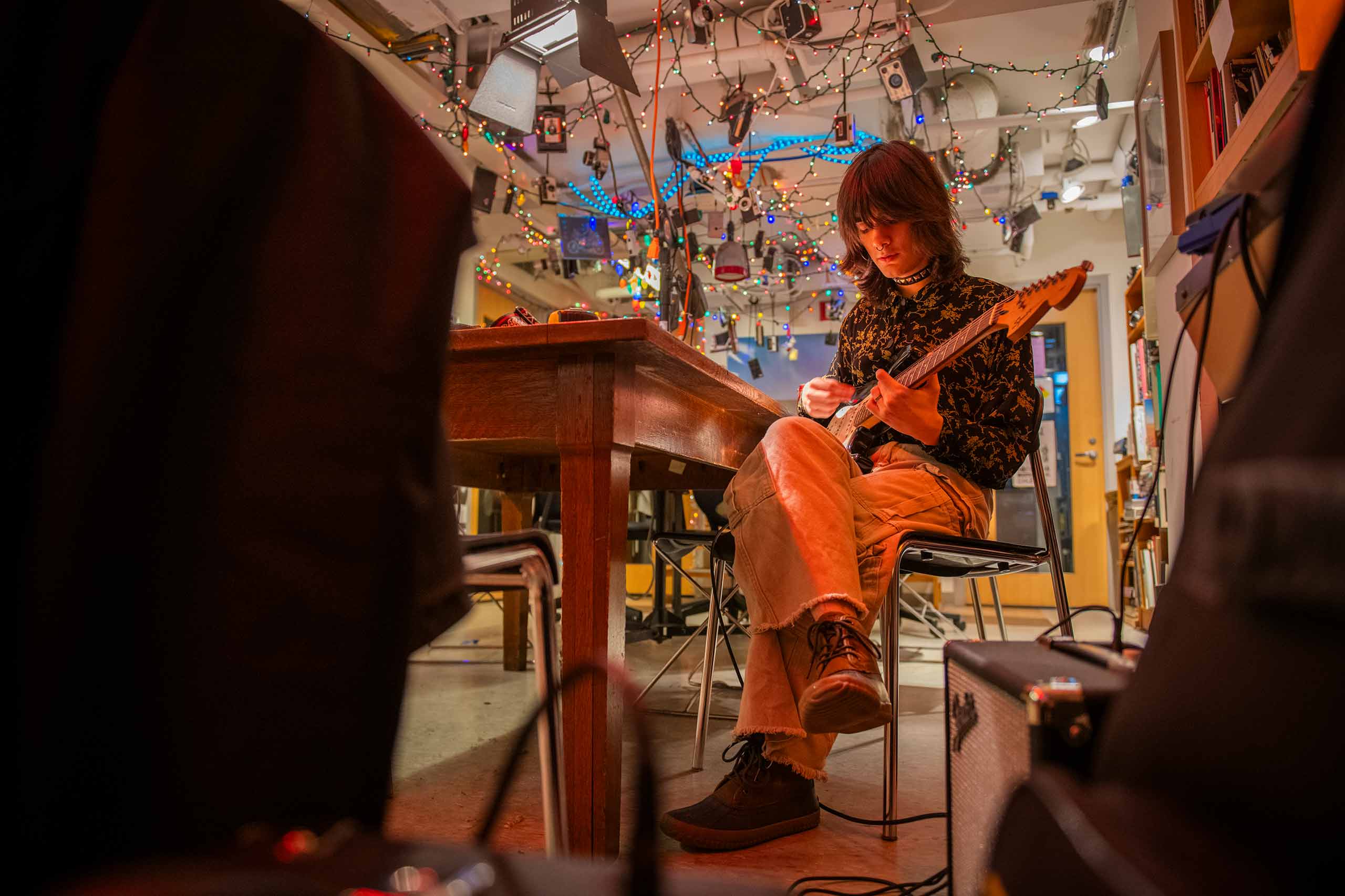 Student tuning a guitar in the photography classroom.