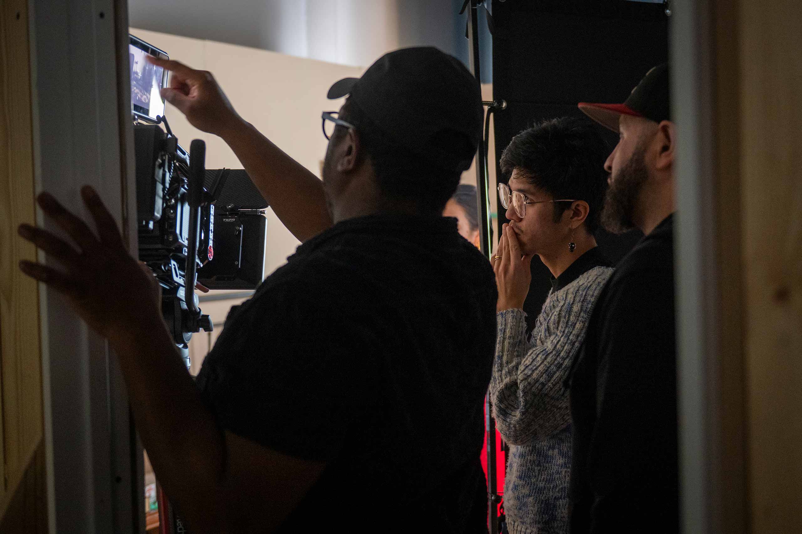 Students examine camera footage during a film shoot.