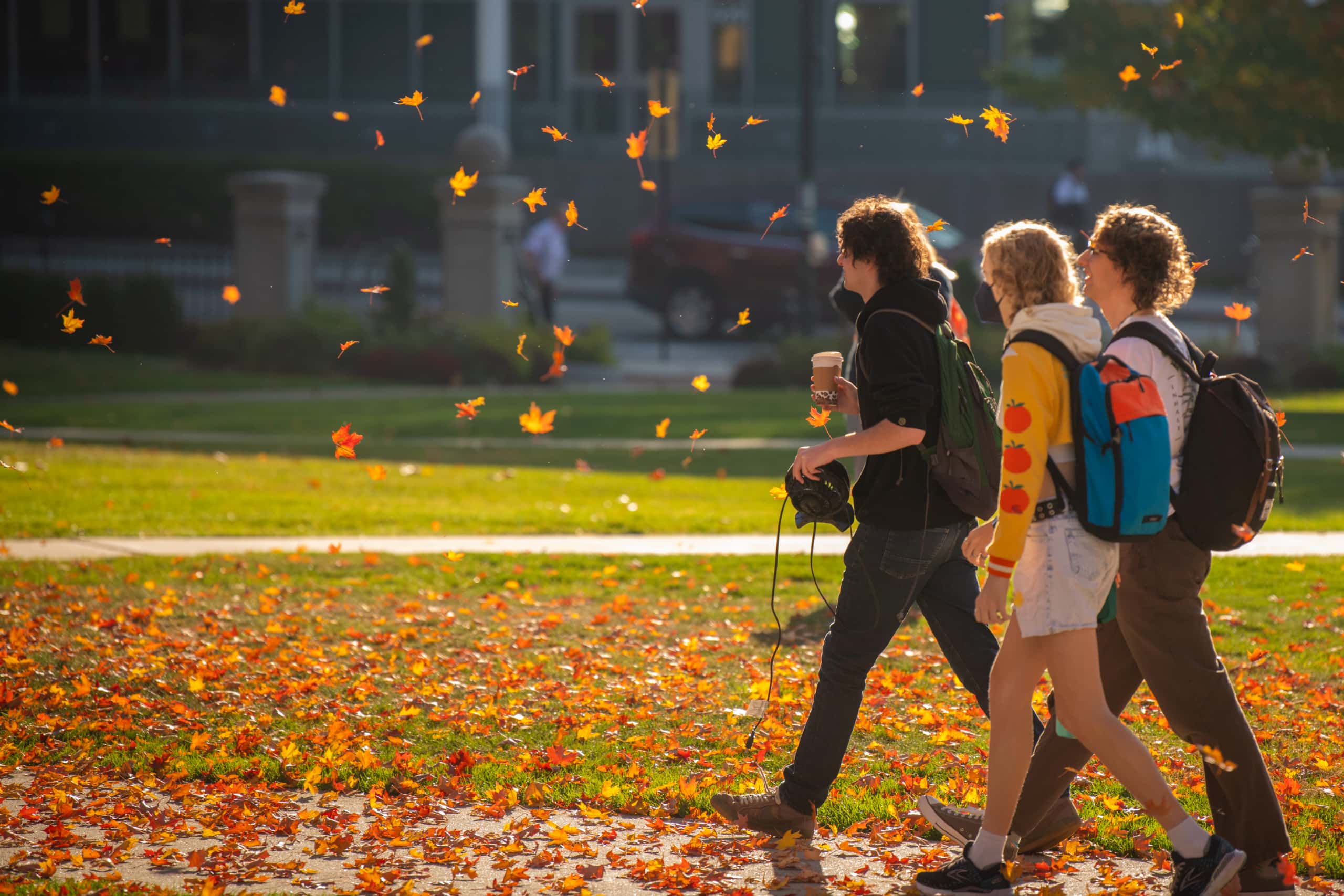 students walking through autumn leaves
