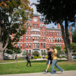 Student walking across Clark University campus in front of Jonas Clark Hall