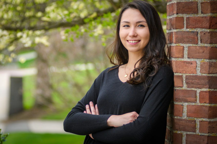 Rachael Chen leaning on brick wall