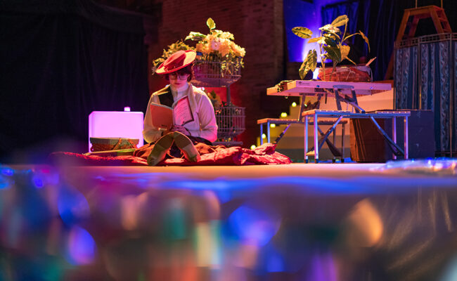 theatre arts - female student sitting on stage with flowers and books - Victorian style