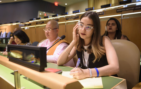 student listening to a listening device and looking at notes