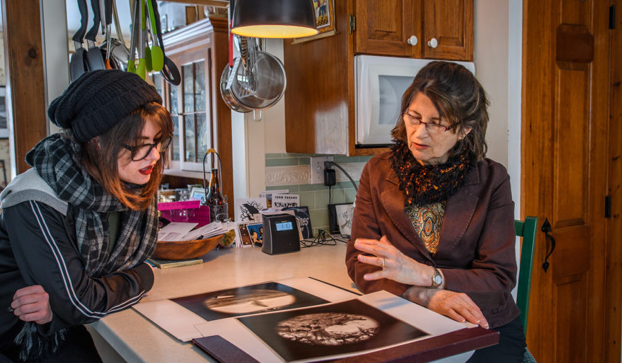 professor looking over art with student in kitchen