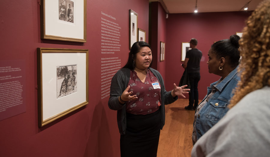 Students reviewing art on a wall exhibit wall