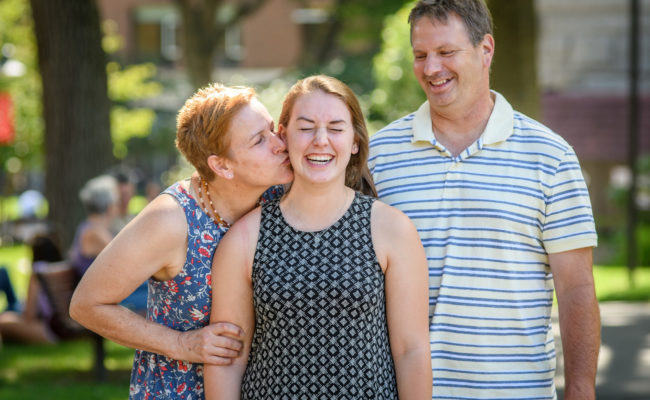 mom kissing daugher on chee