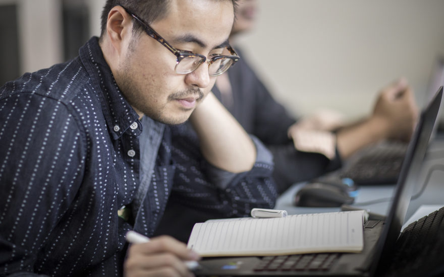 male student writing in notebook