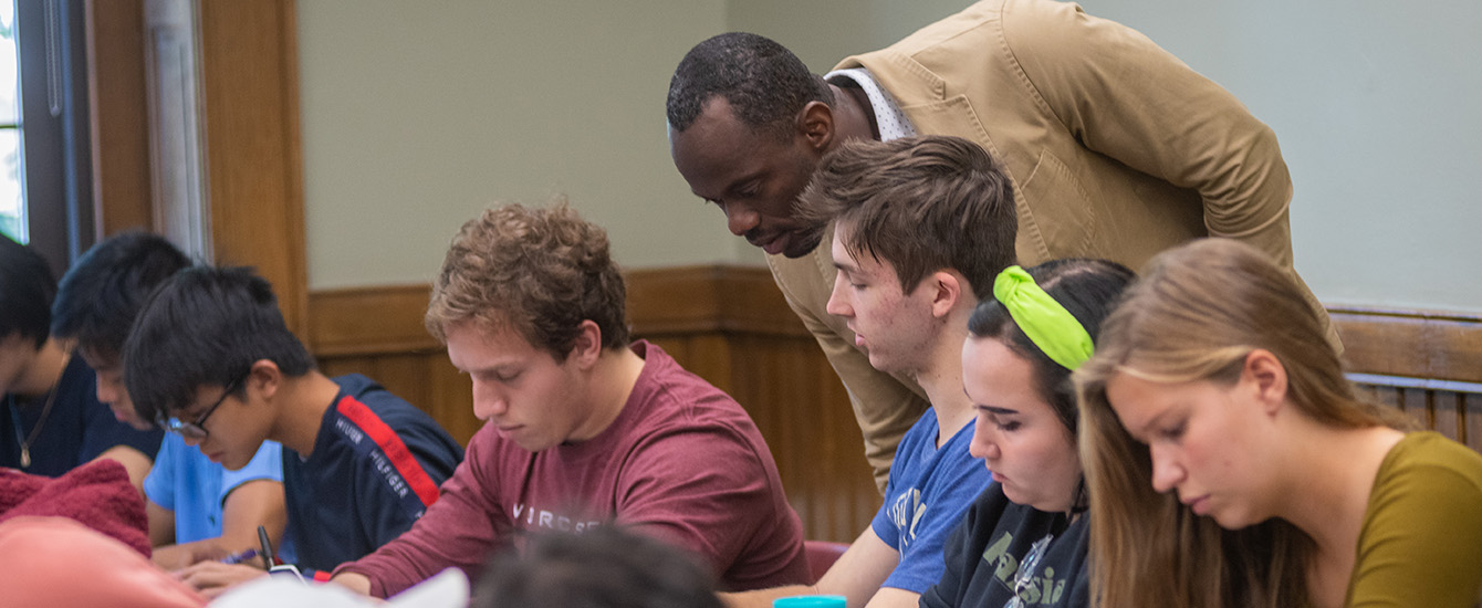 Professor looking over shoulder of student working in class