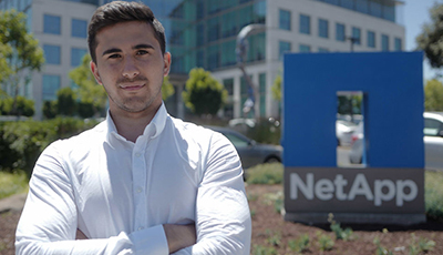 Student standing in front of NetApp sign