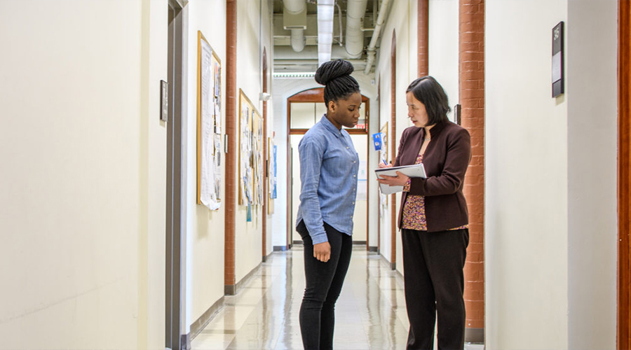 professor speaking to student in hall way