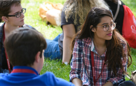 students sitting on campus green