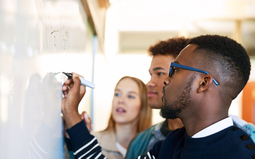 Students writing equation on whiteboard