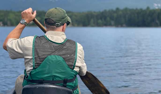 Andrew Vietze ’91 padding canoe on lake surrounded by mountains