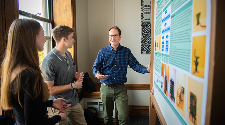 Students and professor reviewing presentation board at ClarkFEST 2024
