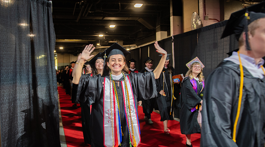 Student with hands raised in air at commencement