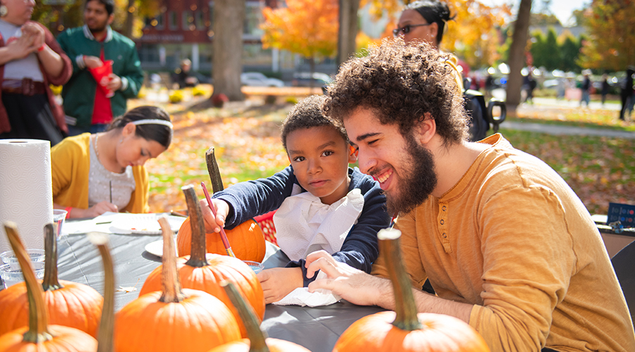 Student and sibling painting pumpkins at family weekend 2024