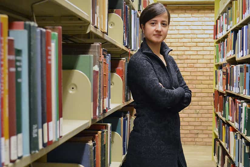 a student poses among the library stacks