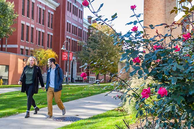 a student and professor walk across campus
