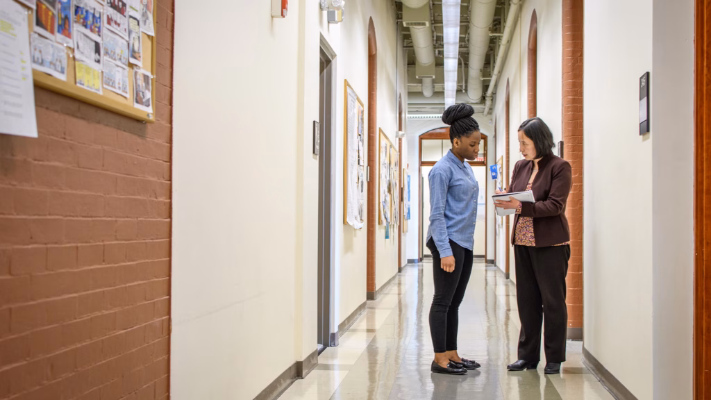 A professor checking in with a student in a corridor