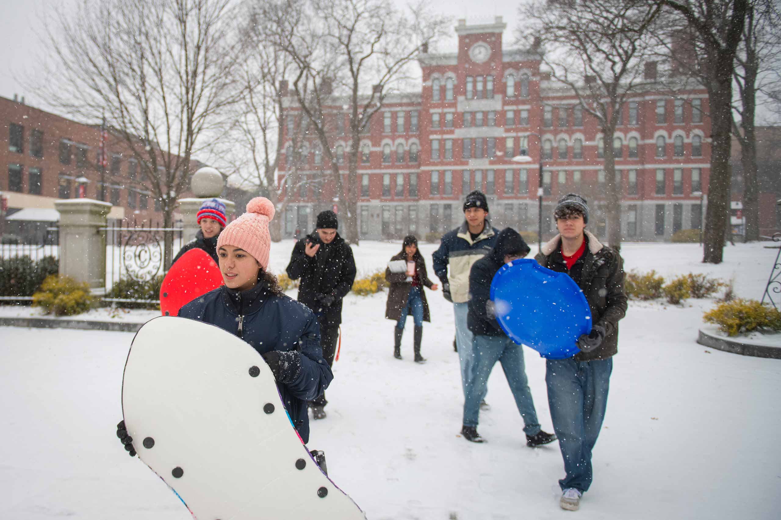 Students in front of Jonas hall during the first snow of the year, carrying sleds