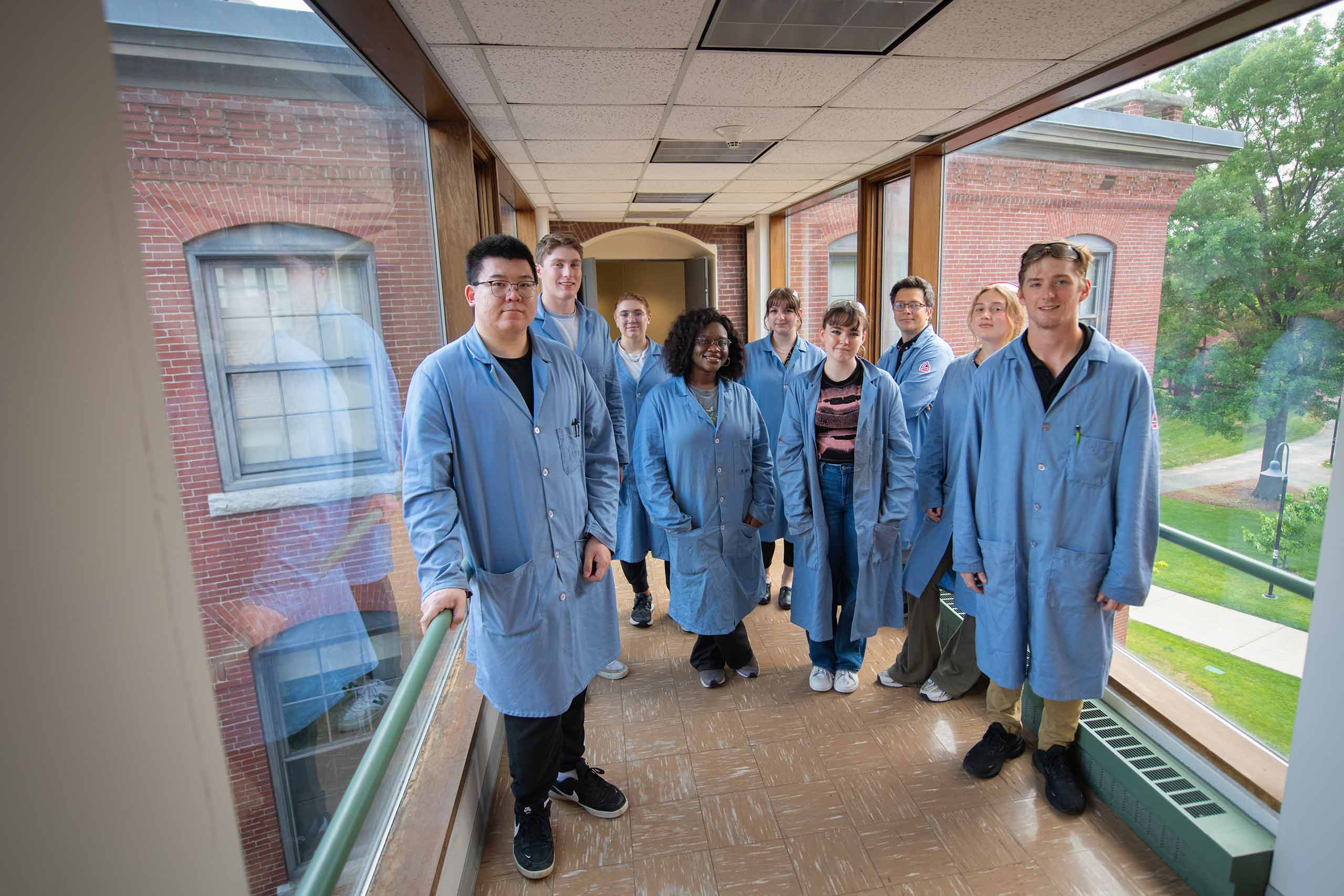 Julio D'Arcy with student researchers in a glass covered corridor.
