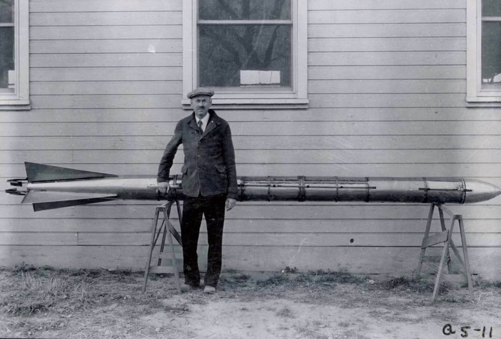 Archival photo of Robert H. Goddard standing with a rocket.