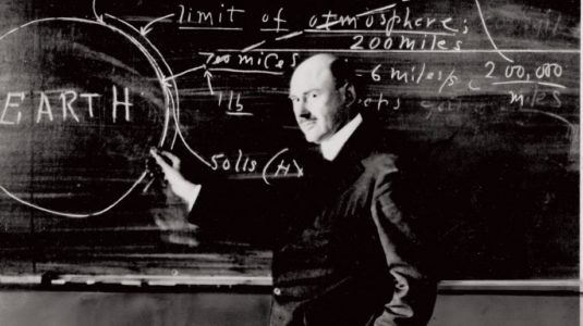 Robert Goddard posing with writings on a blackboard