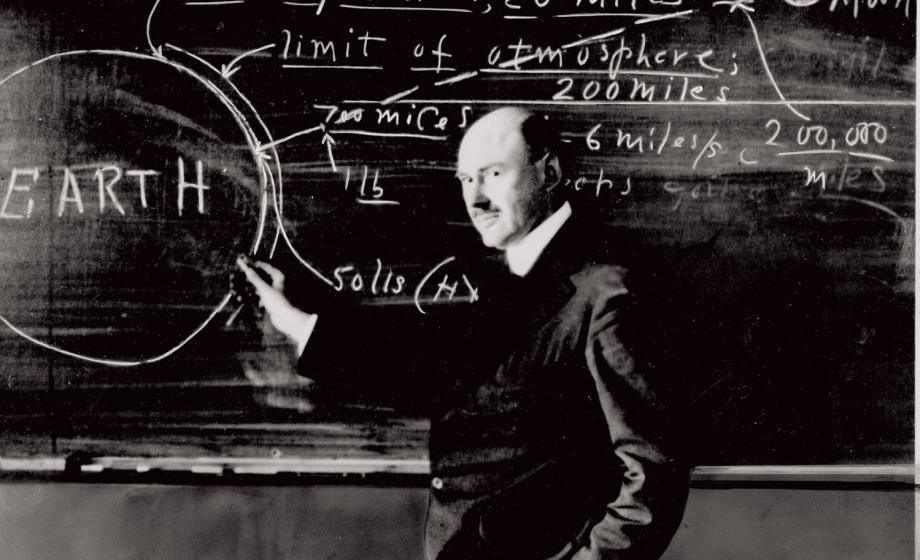 Robert Goddard posing with writings on a blackboard