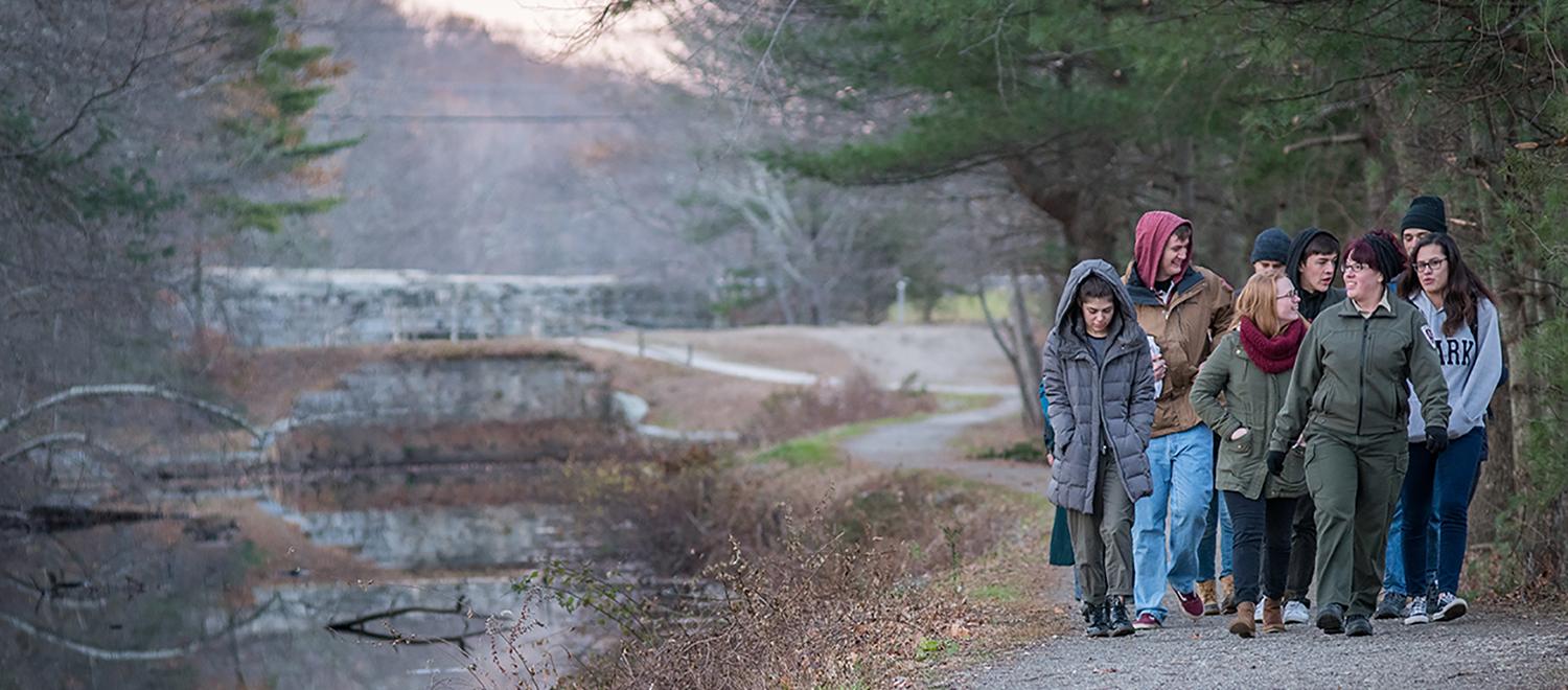 students walking down path near mill