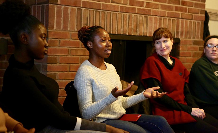 female students sitting in front of fireplace discussing issues