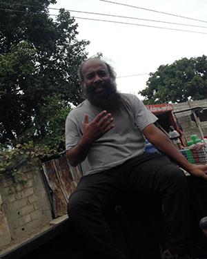 Clark University Associate Professor Jude Fernando teaches while sitting on the bed of a pickup truck in Haiti.