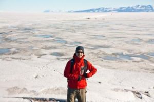 Luke Trusel, postdoctoral scholar at Woods Hole Oceanographic Institution, stands near sea ice covered in melt ponds at McMurdo Station in Antarctica, in 2010. Trusel received a Ph.D. in geography at Clark University in 2014.