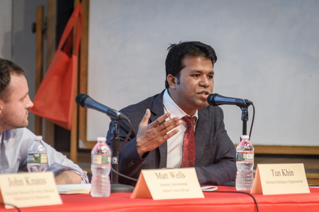 Tun Khin, seated at table, speaks while panelist Matt Wells looks on