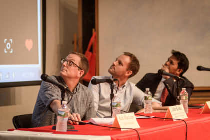 Royhinga panelists, seated, look at screen