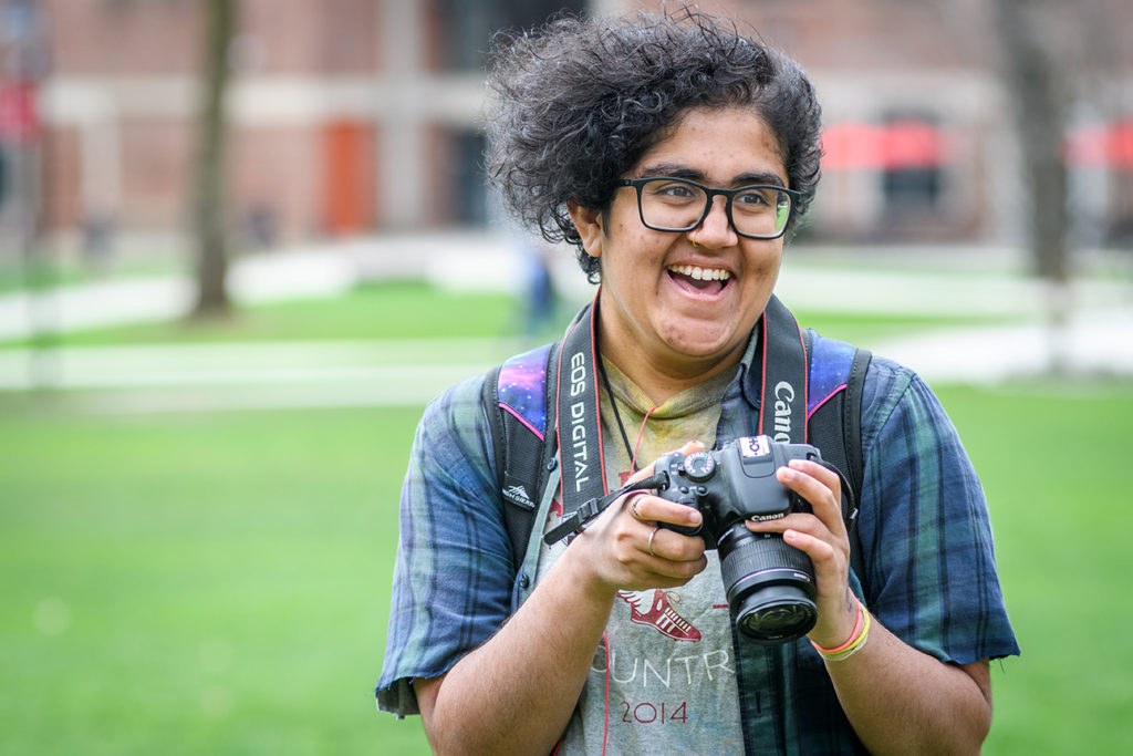 Jay Sundar Rajan with her camera, standing on cmapus green