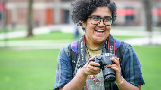 Jay Sundar Rajan with her camera, standing on cmapus green