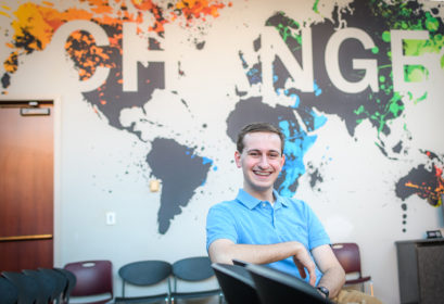 Curan A. VanDerWielen ’21 sits in chair, with words "Change" on wall behind him